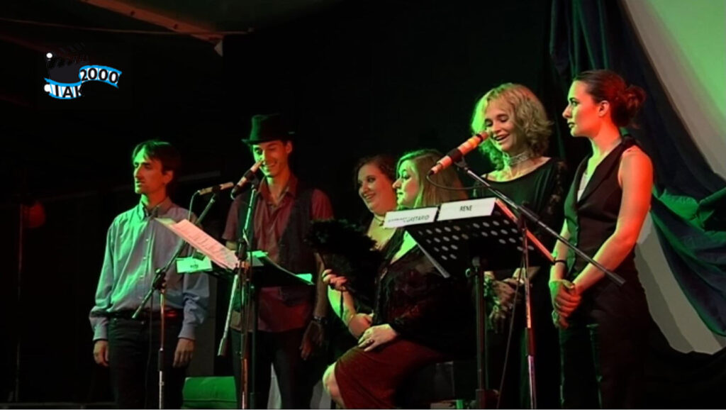 Gruppo di attori e cantanti sul palco per la performance di satira politica Commedia Bluff.
